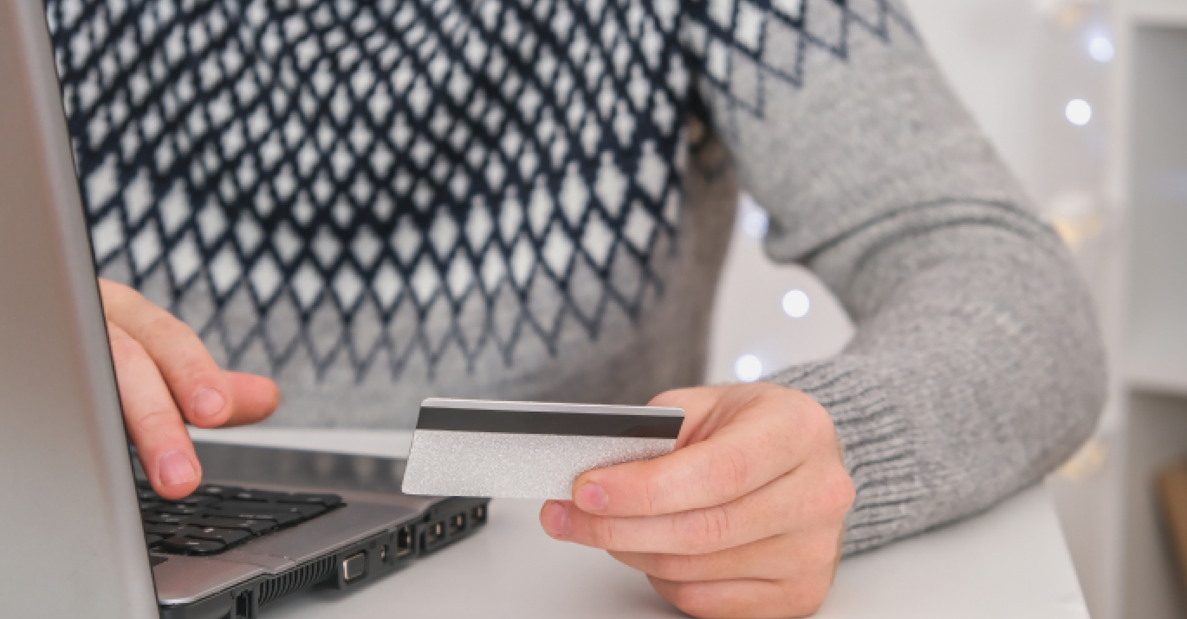 Man holding credit card and using laptop.
